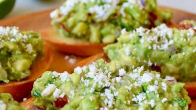 Guacamole bruschetta toasts on a wooden plate